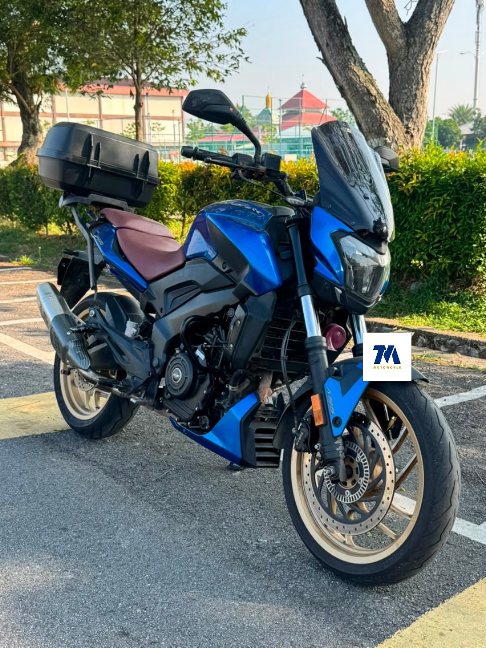 Front 3/4 view of a blue motorcycle with a top box in a parking lot