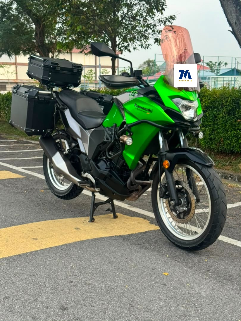 Front three-quarter view of the green motorcycle with panniers.