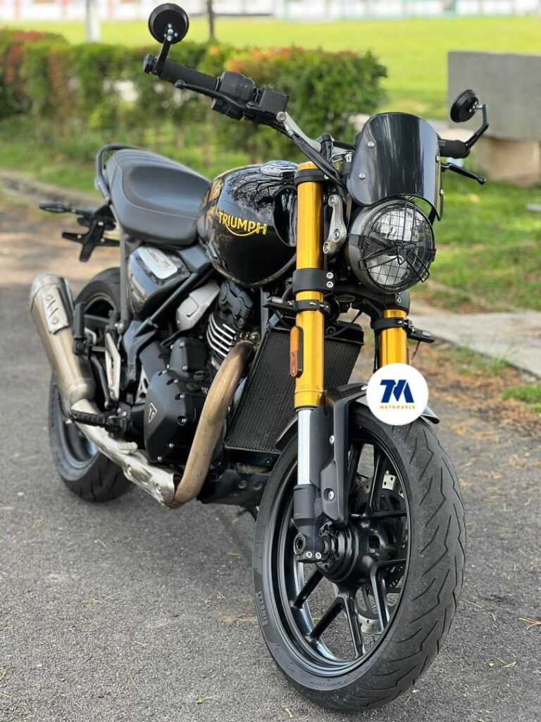 Front-facing view of a Triumph motorcycle with distinctive headlights pointing towards the camera.