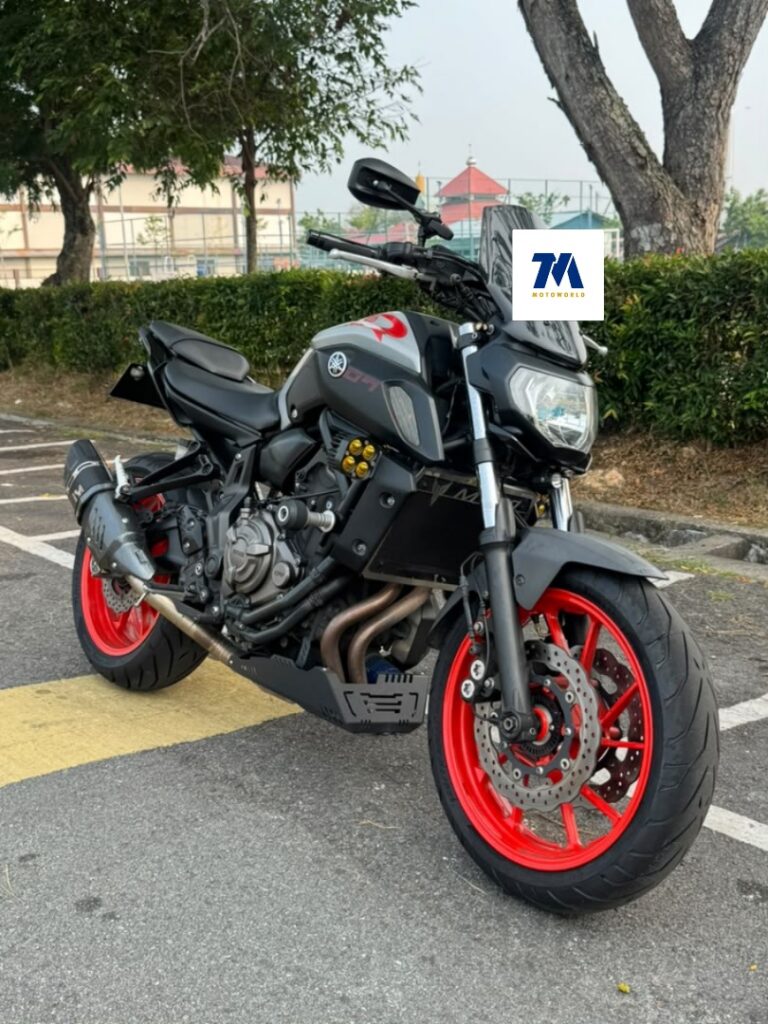 Yamaha MT07 motorcycle with red wheels facing the camera, in a parking lot.