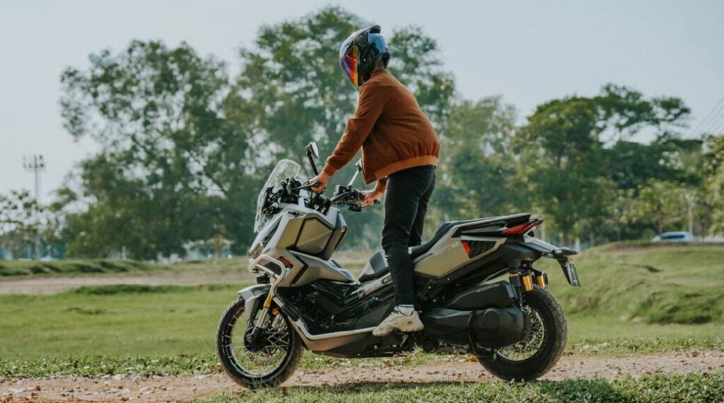 Rider standing on the footboards of a Zontes 368G V2.1 adventure scooter on a gravel track
